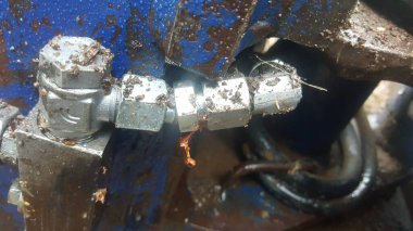 Çamur ve yağla kaplı metal hidrolik eşleşmesinin detaylı görüntüsü endüstriyel ekipmanlarda aşınma ve yıpranma olduğunu gösteriyor.