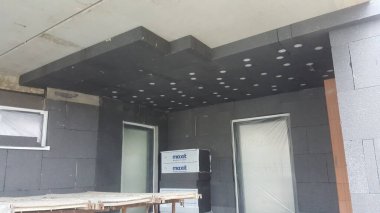 Dış duvarları ve tavanı gösteren inşaat alanı koyu gri yalıtım köpük blokları ve panellerle kaplı, bitirmeye hazır.