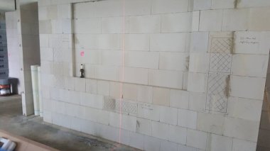 Bir inşaat alanı havalanan beton bloklardan oluşan bir duvar gösteriyor. Üzerinde işaretler var. Ve bir lazer seviyesi.