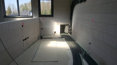 Havalandırmalı beton blok duvarları, su tesisatı ve elektrik kabloları olan ve tamamlanmayı bekleyen bir oda.