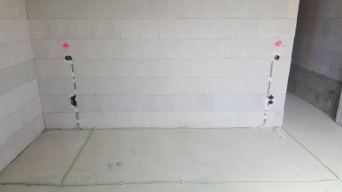 Elektrik hatları ve bağlantı kutuları inşaat halindeki bir binanın duvarlarında ve zemininde son rötuşları bekliyor.