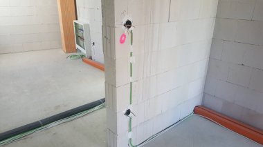 İnşaat aşamasında bir binanın beton blok duvarları içine yeni elektrik kabloları ve kablolar yerleştiriliyor.