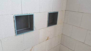 Tamamlanmamış duvarda döşeme ya da bitirme için hazır iki kare açıklık var, entegre raf inşa sürecini gösteriyor