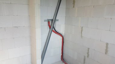 Görünür elektrik hatları ve kablolar bir inşaat sahasının bitmemiş iç kısımlarına kuruluyor ve bu da altyapı inşaatının ilk aşamalarını gösteriyor.