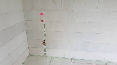 Tamamlanmamış beton duvarları olan bir binaya yeni elektrik kablosu ve bağlantı kutuları yerleştiriliyor.