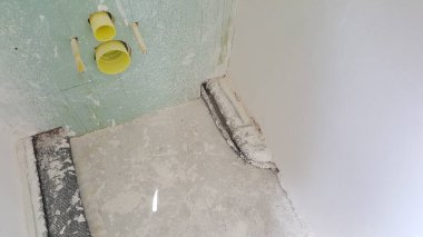 Tesisat boruları, alçıpan ve beton döşemeleri görünen ağ takviyeli bir banyo.