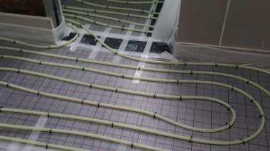 Installation of radiant floor heating system with pipes secured to insulation panels, preparing for a new floor