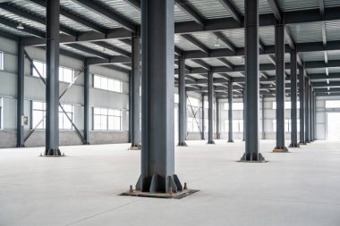 Yüksek tavanı, geniş pencereleri ve sağlam metal destek kirişleri ve kolonları olan boş, modern bir endüstriyel bina.
