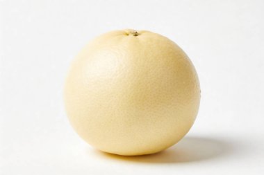 Bütün, soyulmamış sarı greyfurt, pürüzsüz beyaz bir yüzeyde izole bir şekilde, yumuşak bir gölge oluşturur.