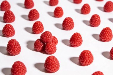 Olgun ahududu minimalist bir düzenleme temiz beyaz arka planda güçlü zıt gölgelerle görsel olarak çekici bir desen oluşturur.