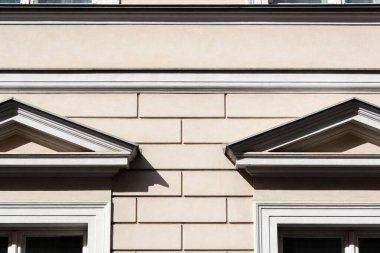 Bir binanın dış yüzeyindeki klasik mimari elementlerin yakın görüntüsü, simetri ve geometrik desenleri gösteriyor