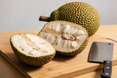 Koca bir meyve büyük, dikenli bir meyvenin arkasında oturur ikiye bölünmüş, lifli iç kısımları ve tohumları ortaya çıkar, ahşap bir yüzey üzerinde bir satır ile birlikte.