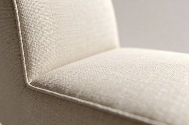 Sığ bir alan derinliği, tarafsız renkli bir tekstil olan mobilyanın karmaşık dokusunu ve yumuşak dokusunu vurgular.