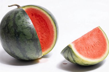 A whole watermelon with a slice removed, revealing its vibrant red flesh and seeds, set against a clean white backdrop