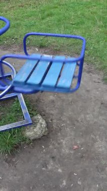 Solitary Blue Carousel Seat on Playground with Overcast Sky, Evoking Childhood Memories and a Touch of Abandonment, Ideal for Nostalgic, Children-themed Concepts