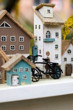 Lezzetli Minyatür Köy Kompozisyonu: El Boyalı Ahşap Evlerin Yakın Çekimi, Karmaşık Ayrıntılar ve Siyah Bisiklet Figürü, Sanatsal ve Nostaljik Raflar