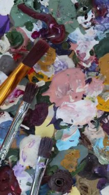 Kullanılmış yağlı boya ve fırça çeşitleriyle dolu canlı bir sanat paletinin yukarıdan aşağı görüntüsü, yaratıcı bir sanat arkaplanının somutlaştırılması, sanat ve yaratıcılığın özünü temsil etmesi, temel sanat malzemelerini sergilemesi
