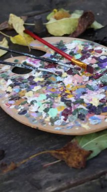 Kullanılmış ahşap palet, fırça, mavi ortanca küçük bir tablo ve kırsal ahşap bir masa üzerinde dağınık sonbahar yaprakları ve cevizler ile büyüleyici bir sanatçı çalışma alanı, rahat, yaratıcı bir atmosfer yaratmak