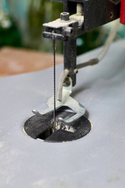 Tahtayı kesen ince bıçaklı bir testerenin detaylı görüntüsü, masaya talaş bırakması, karmaşık ahşap işçiliği projeleri için hassas aracı vurgulaması.