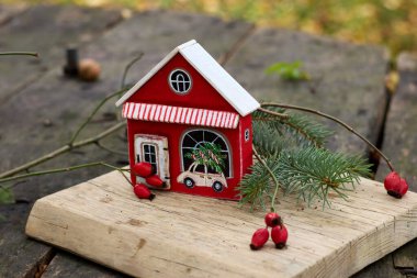 Yılbaşı şenliklerinde, Noel ağacı arabasıyla boyanmış ahşap bir ev minyatürü, gümüşten böğürtlenler ve kırsal ahşap bir yüzey üzerinde taze bir köknar dalı yer alıyor..