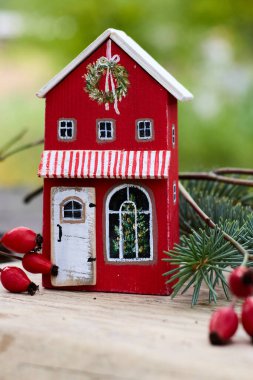 Detaylı bir çekim, güzel, el yapımı ahşap bir Noel evi yakalıyor, canlı bir şekilde boyanmış ve Noel temalı detaylarla süslenmiş, bulanık, doğal bir dış görünüş ile tamamlanmış, şenlikli cazibesini ve cazibesini arttırıyor..