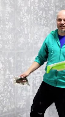 Odaklanmış bir zanaatkar, bir mala kullanarak duvara dekoratif alçı uygular, ustalıkla dokulu bir kapanış yaratır, iç tasarımda profesyonel uzmanlıklarını gösterir, mekandaki estetik cazibeyi hassasiyetle artırır