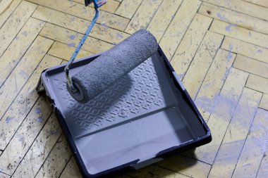 Ringa kemiği ahşap zemininde, boyanmaya hazır gri boyanmış boya tablasını kapat. Bu görüntü, evin iç dekorasyonunun özünü, kendin yap projesini ve boyanın dönüştürücü gücünü, yenileme konseptini yansıtıyor.,