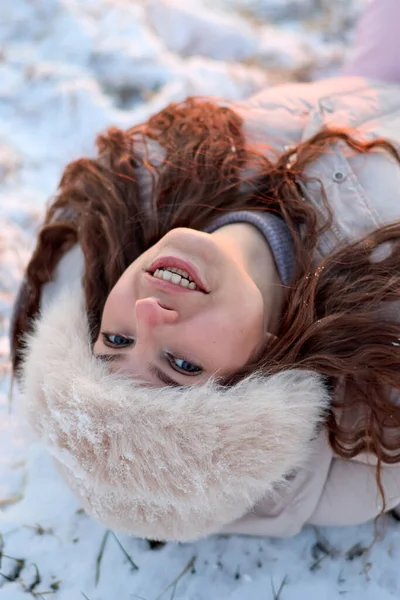 Kış günü kar altında sırtüstü yatarken sırtüstü gülümseyen uzun kıvırcık kumral saçlı ve mavi gözlü çekici genç bir kadın, rahat bir kürk şapkası ve kışlık ceketi vardı..