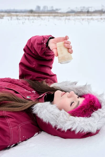 Güzel bir genç kadın, rahat bir kışlık ceket giymiş, kürklü bir başlıklı, karda yatıyor ve baş aşağı duran bir dondurma külahını tutuyor, düşüncelerinde kayboluyor ve kış gününün tadını çıkarıyor..