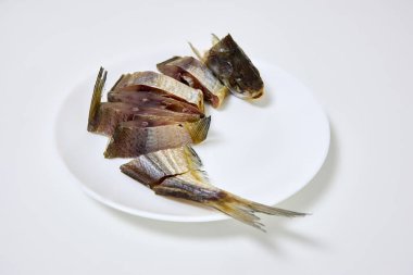 Dilimlenmiş balıkların yakın çekimleri, beyaz bir tabakta, katıksız bir zemin üzerinde sunuluyor, aşçılık ve yemek temaları için karmaşık doku ve hazırlık tarzını gözler önüne seriyor, eğitici veya ticari amaçlara uygun ayrıntılı bir görünüm sunuyor.