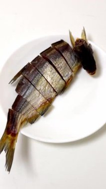 Beyaz bir tabakta dilimlenmiş balığın detaylı görüntüsü, yemek blogları, mutfak rehberleri ve gastronomi meraklıları için mükemmel..