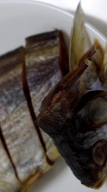 Dilimlenmiş kısımların yanında kurumuş balık kafasının görüntülendiği detaylı makro çekim, geleneksel gıda koruma yöntemini vurguluyor, doku ve hazırlığa odaklanıyor..