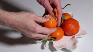 Ellerinizi kapayın ve portakalı muz ve diğer mandalinalarla dolu yaprak şeklindeki meyve kasesinden nazikçe sıyırın.