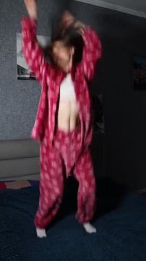 Canlı pijamalarıyla neşeli genç bir kadın yatağında dans ediyor. Sabah enerjisini ve özgürlüğünü somutlaştırıyor. Neşeli ve tasasız bir yaşam tarzı sergiliyor..