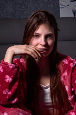 Pofuduk bir elbise içindeki genç bir kadının büyüleyici portresi, düşünceli bir şekilde ileriye bakıyor, eli nazikçe dudaklarına dokunuyor, içsel bir yansıma ve sessiz bir güven ortamı yaratıyor..