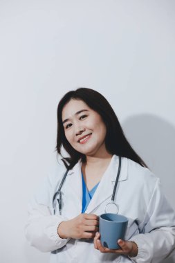 Beyaz stüdyo arka planında elinde kahve fincanı tutan Asyalı kadın portresi.