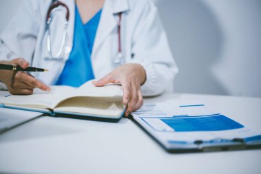 Doktorun odasında dizüstü bilgisayarla çalışan orta yaşlı bir kadın doktor.