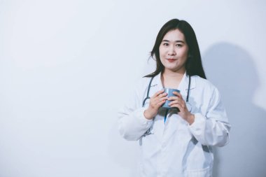 Beyaz stüdyo arka planında elinde kahve fincanı tutan Asyalı kadın portresi.