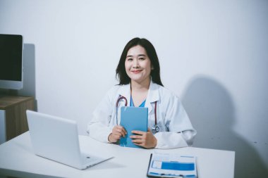 Doktorun odasında dizüstü bilgisayarla çalışan orta yaşlı bir kadın doktor.