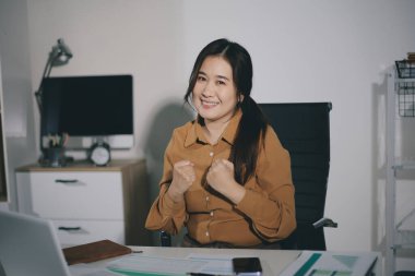 Masa başındaki bilgisayarda çalışan odaklanmış muhasebeci belgeleri yakın çekimde tutuyor..