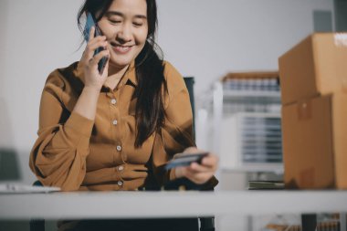 Çevrimiçi ödeme, kredi kartı tutan ve online alışveriş için akıllı telefon kullanan kadının elleri.