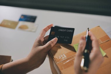 Çevrimiçi ödeme, kredi kartı tutan ve online alışveriş için akıllı telefon kullanan kadının elleri.