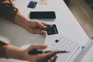 Çevrimiçi ödeme, kredi kartı tutan ve online alışveriş için akıllı telefon kullanan kadının elleri.