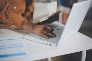 Business woman using calculator to calculate financial report, working at office with laptop computer on table. Asian female accountant or banker making calculations. finances and economy concept