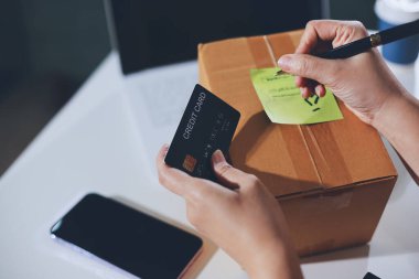 Çevrimiçi ödeme, kredi kartı tutan ve online alışveriş için akıllı telefon kullanan kadının elleri.