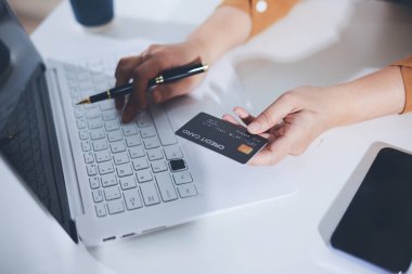 Çevrimiçi ödeme, kredi kartı tutan ve online alışveriş için akıllı telefon kullanan kadının elleri.