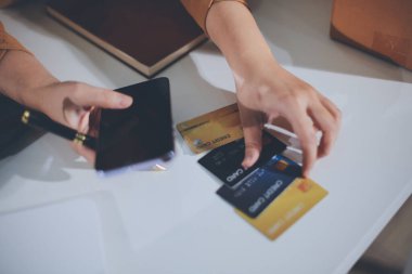 Çevrimiçi ödeme, kredi kartı tutan ve online alışveriş için akıllı telefon kullanan kadının elleri.