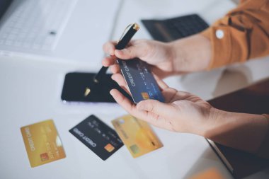 Çevrimiçi ödeme, kredi kartı tutan ve online alışveriş için akıllı telefon kullanan kadının elleri.