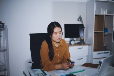 Business woman using calculator to calculate financial report, working at office with laptop computer on table. Asian female accountant or banker making calculations. finances and economy concept