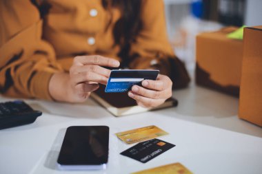 Çevrimiçi ödeme, kredi kartı tutan ve online alışveriş için akıllı telefon kullanan kadının elleri.